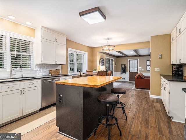 kitchen featuring butcher block countertops, a sink, stainless steel dishwasher, decorative backsplash, and dark wood-style floors