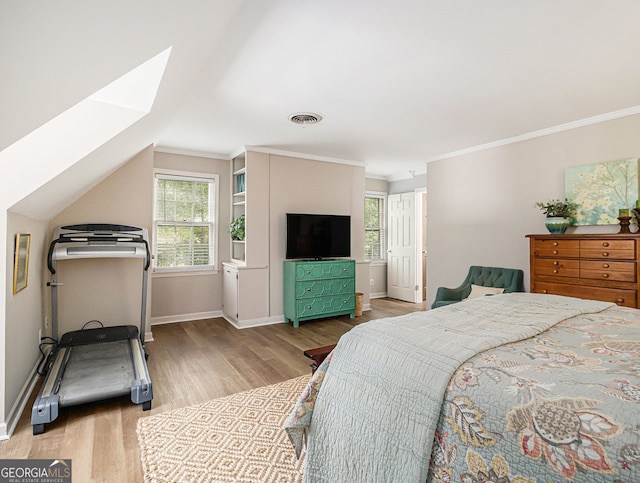 bedroom with visible vents, crown molding, baseboards, and wood finished floors