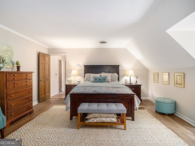 bedroom featuring visible vents, baseboards, lofted ceiling, ornamental molding, and wood finished floors