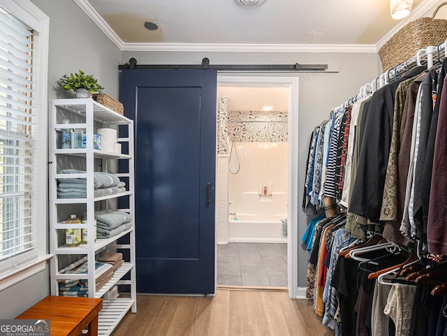 walk in closet with a barn door and wood finished floors