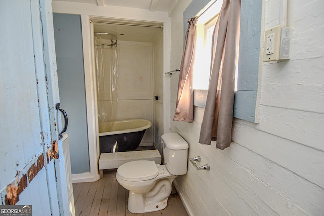 bathroom with a bathing tub, hardwood / wood-style flooring, and toilet