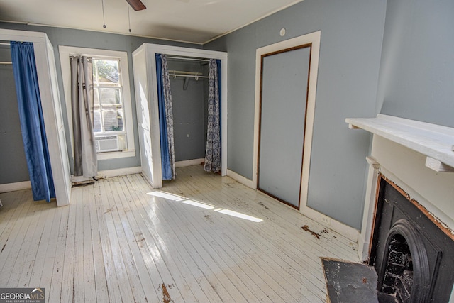 unfurnished bedroom featuring ceiling fan, light hardwood / wood-style floors, and cooling unit