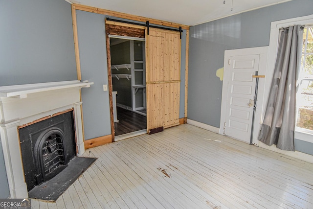 unfurnished living room featuring light wood-type flooring and a barn door