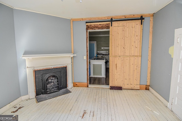 unfurnished living room featuring a barn door and wood-type flooring