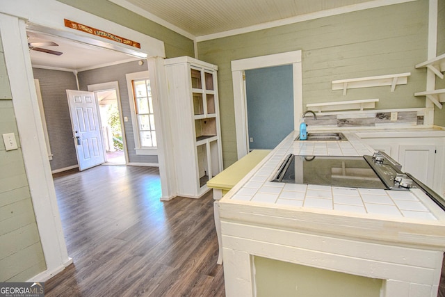 kitchen with tile countertops, stainless steel stovetop, dark wood-type flooring, sink, and ornamental molding