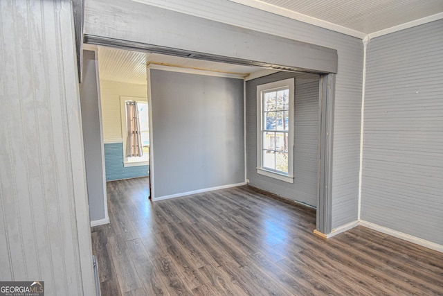 spare room featuring wood walls, crown molding, and dark wood-type flooring