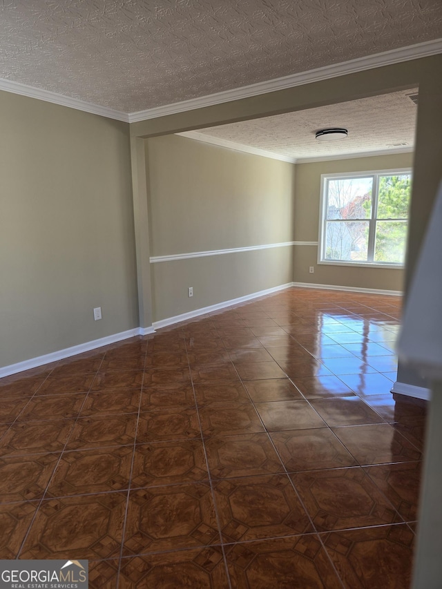 spare room featuring a textured ceiling, dark tile patterned floors, and ornamental molding