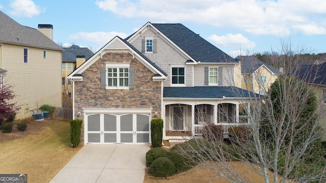 view of front of home featuring covered porch, cooling unit, a garage, and a front yard