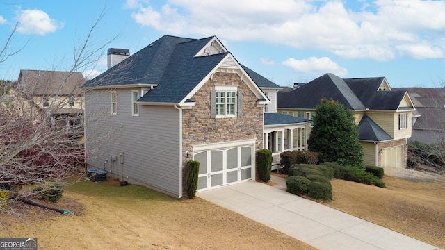 view of front of property with a chimney, concrete driveway, an attached garage, stone siding, and a front lawn