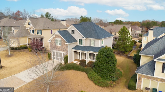 view of front of house with an attached garage, a shingled roof, driveway, a residential view, and a chimney