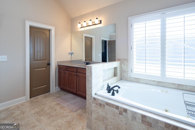 bathroom featuring vanity, vaulted ceiling, tiled bath, and plenty of natural light