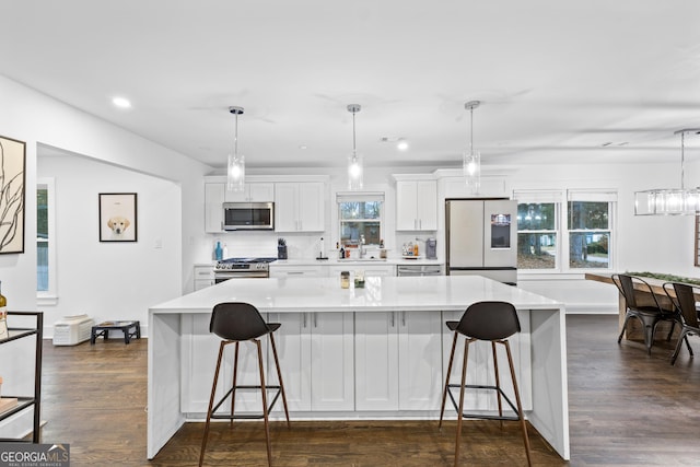 kitchen with dark wood-type flooring, white cabinets, pendant lighting, and appliances with stainless steel finishes