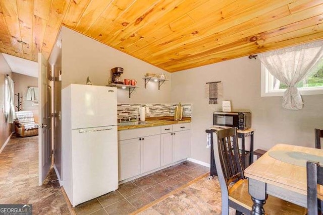 kitchen featuring lofted ceiling, white cabinetry, decorative backsplash, white fridge, and wood ceiling