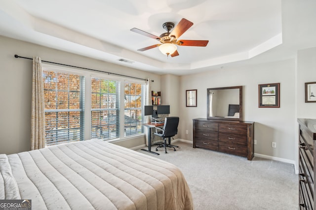 bedroom with a tray ceiling, baseboards, visible vents, and carpet