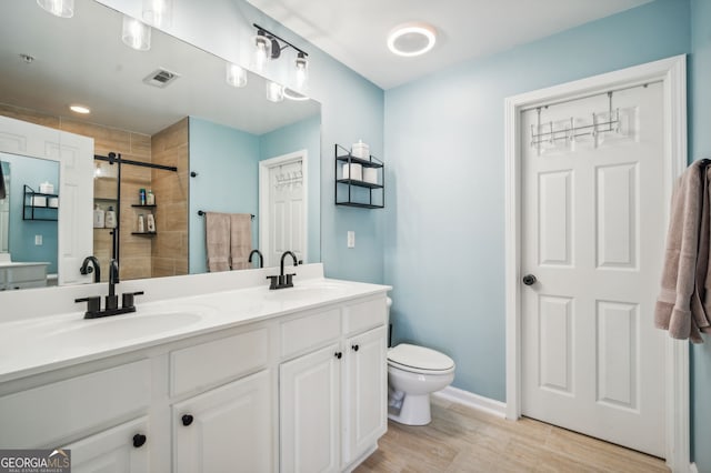 full bathroom with visible vents, a sink, a tile shower, and toilet