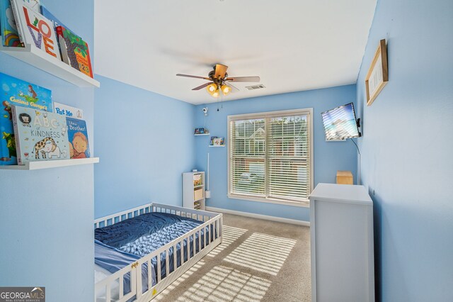 bedroom featuring carpet floors, visible vents, a ceiling fan, a nursery area, and baseboards