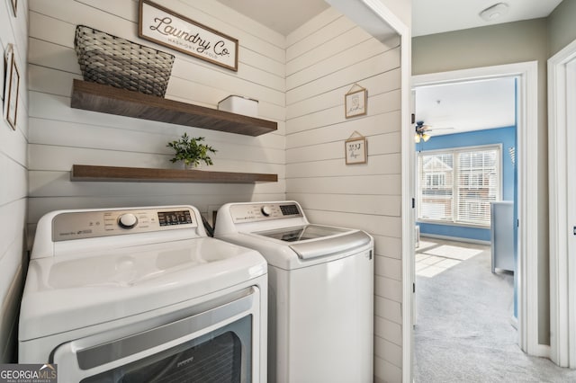 laundry room with carpet, washer and clothes dryer, a ceiling fan, wooden walls, and laundry area