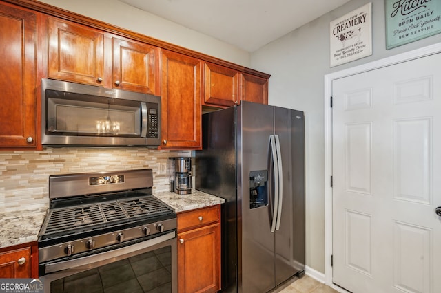 kitchen with appliances with stainless steel finishes, brown cabinets, light stone counters, and decorative backsplash