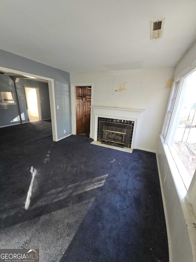 unfurnished living room with a tiled fireplace and carpet floors