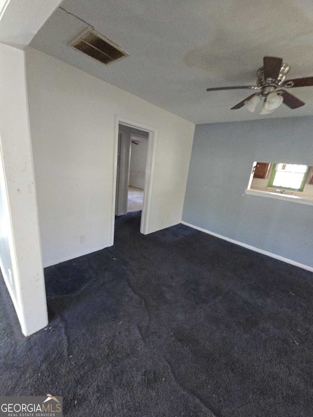 spare room featuring dark colored carpet, ceiling fan, and a textured ceiling