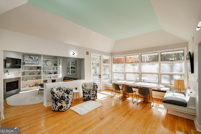 living room with wood-type flooring, vaulted ceiling, and plenty of natural light