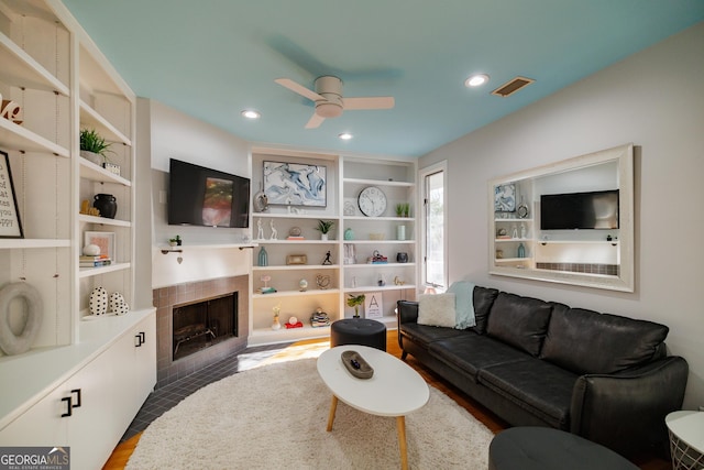 living room with ceiling fan, dark hardwood / wood-style floors, and a tiled fireplace