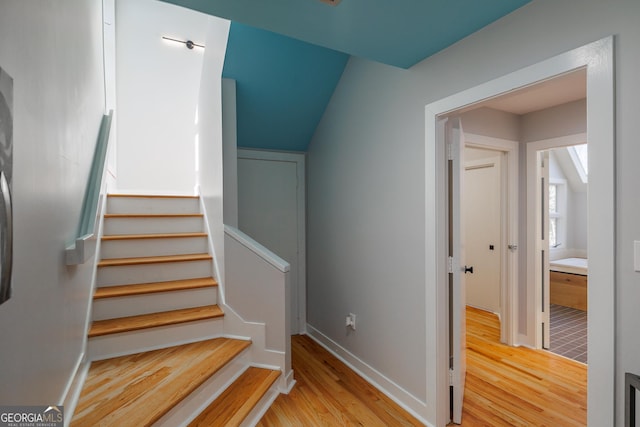 stairway featuring wood-type flooring and vaulted ceiling