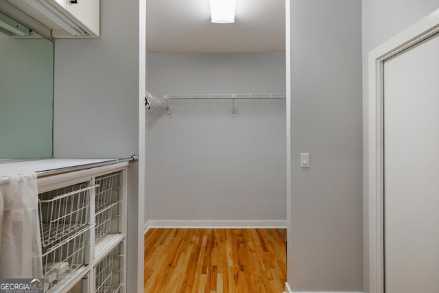 walk in closet with light hardwood / wood-style flooring