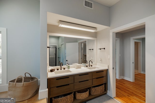 bathroom with hardwood / wood-style floors, vanity, and an enclosed shower