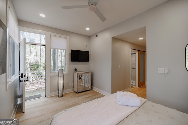 bedroom featuring access to outside, a barn door, ceiling fan, and light hardwood / wood-style flooring