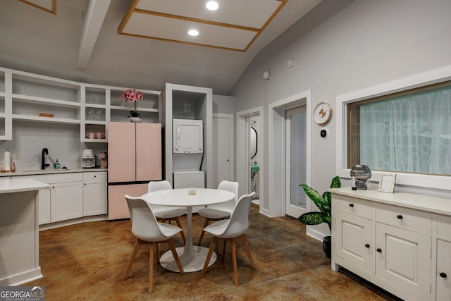 dining room featuring vaulted ceiling with beams, stacked washer / drying machine, and sink