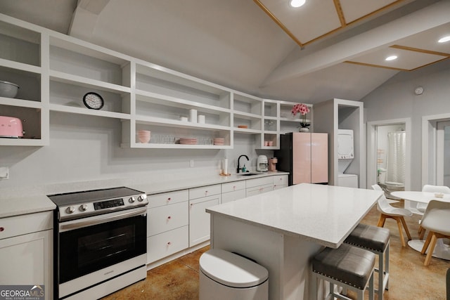 kitchen featuring a kitchen bar, white cabinetry, stacked washer / drying machine, lofted ceiling, and stainless steel electric range