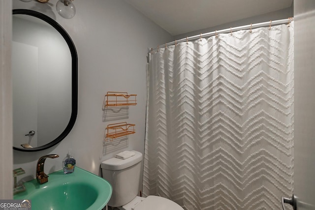 bathroom with toilet, curtained shower, and sink