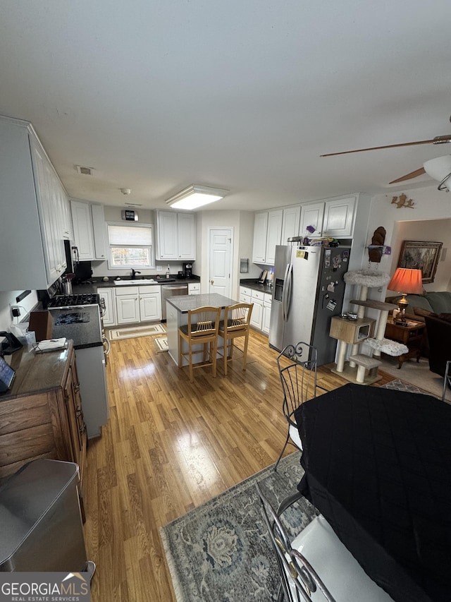 living room featuring light wood-type flooring, ceiling fan, and sink