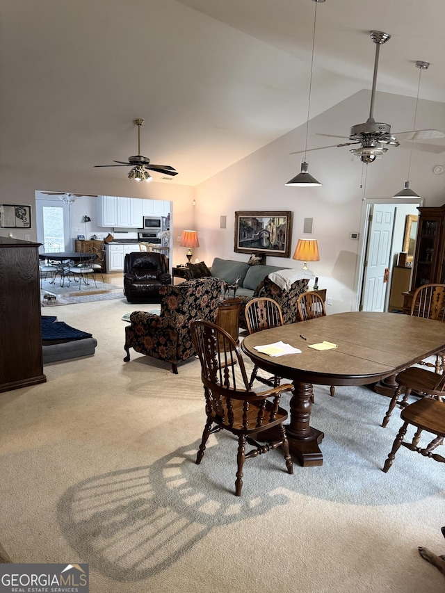 carpeted dining area featuring ceiling fan and lofted ceiling