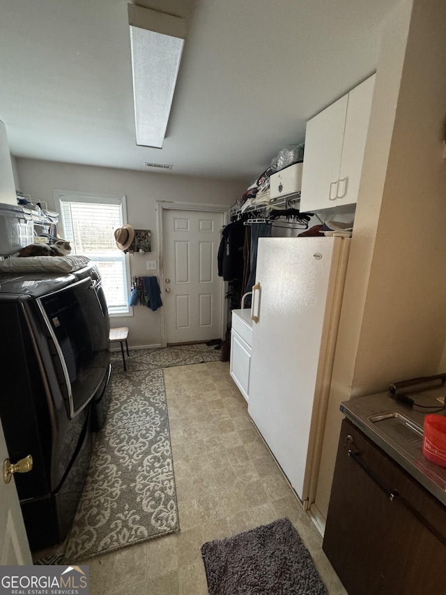 laundry room featuring washing machine and clothes dryer and cabinets