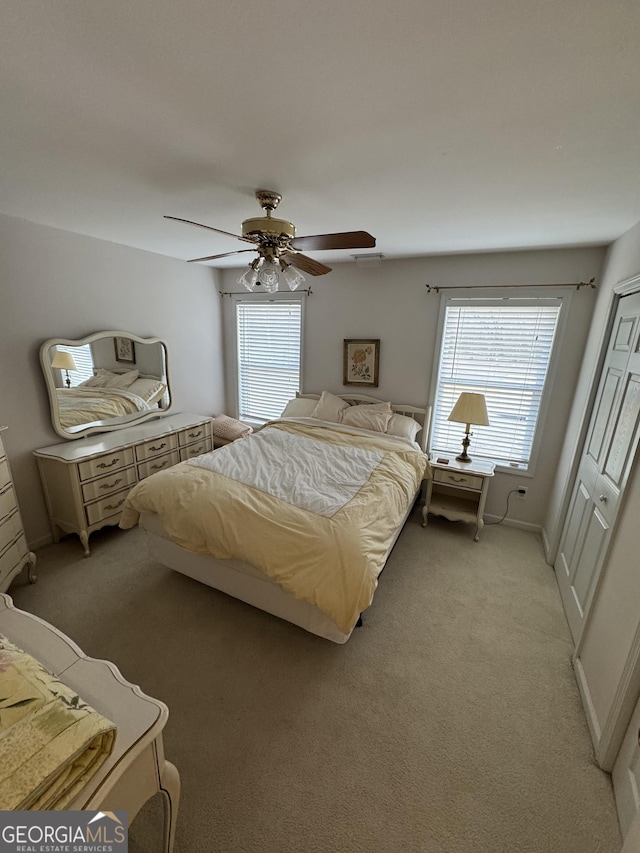 bedroom featuring multiple windows, ceiling fan, and light carpet