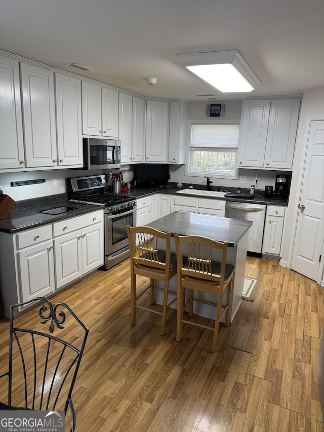 kitchen with white cabinets, light wood-type flooring, sink, and appliances with stainless steel finishes