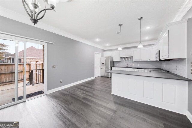 kitchen with an inviting chandelier, hanging light fixtures, decorative backsplash, appliances with stainless steel finishes, and white cabinetry