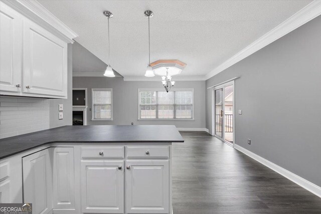 kitchen with kitchen peninsula, tasteful backsplash, crown molding, decorative light fixtures, and white cabinets