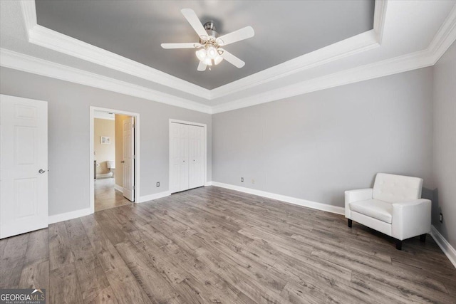 unfurnished room with hardwood / wood-style flooring, ceiling fan, a raised ceiling, and ornamental molding