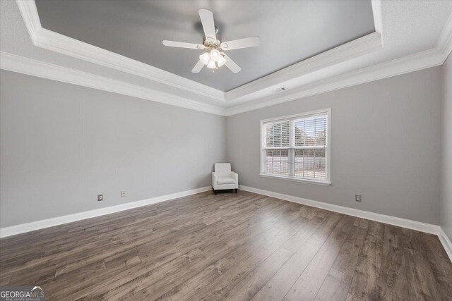 spare room featuring dark hardwood / wood-style flooring, ceiling fan, a raised ceiling, and ornamental molding