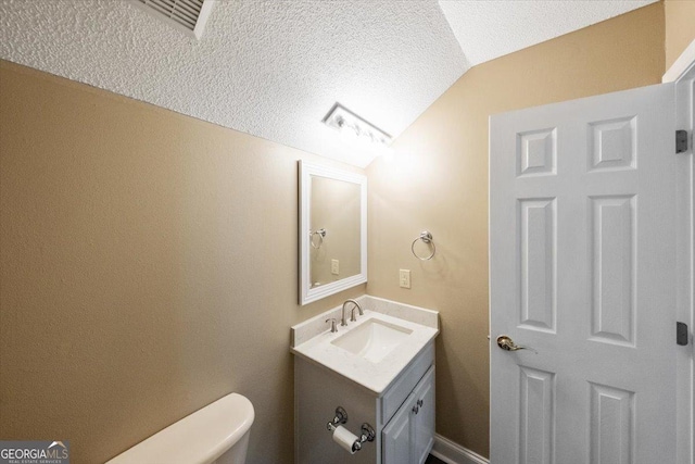 bathroom featuring vanity, toilet, a textured ceiling, and vaulted ceiling