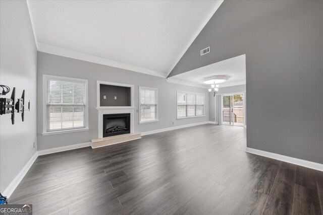 unfurnished living room with dark hardwood / wood-style floors, lofted ceiling, ornamental molding, and a chandelier