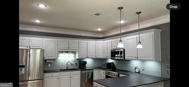 kitchen featuring sink, white cabinets, hanging light fixtures, and appliances with stainless steel finishes