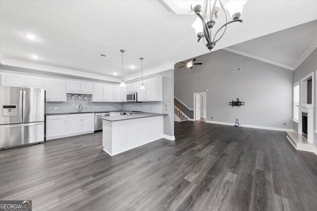 kitchen featuring white cabinets, sink, appliances with stainless steel finishes, decorative light fixtures, and kitchen peninsula