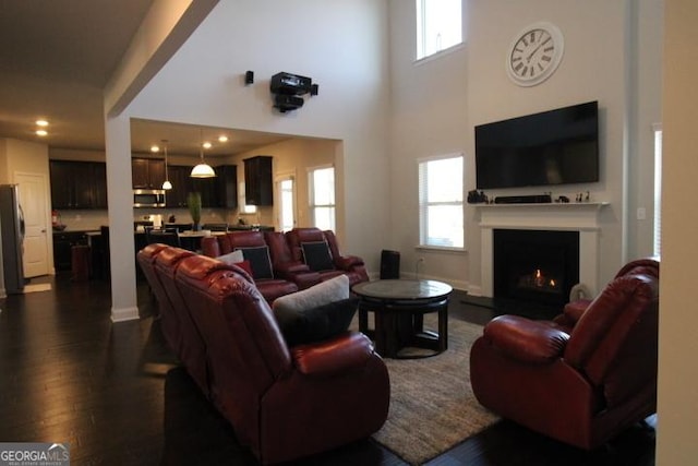 living room featuring a high ceiling, dark hardwood / wood-style flooring, and a healthy amount of sunlight