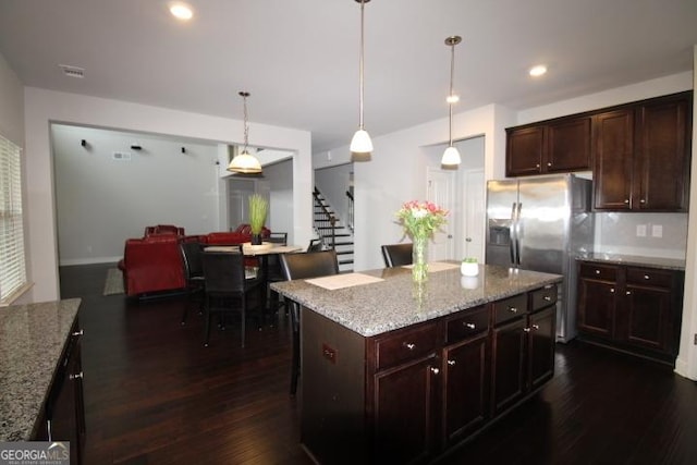 kitchen featuring light stone counters, dark wood-type flooring, a kitchen island, and hanging light fixtures