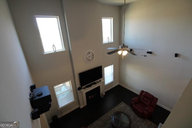 living room with a wealth of natural light, a towering ceiling, and ceiling fan