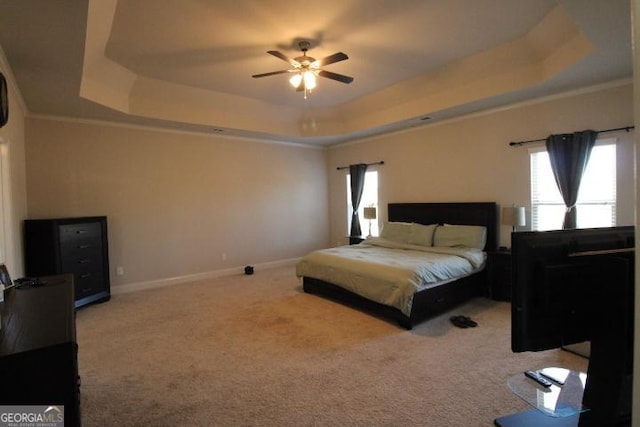 carpeted bedroom featuring ceiling fan, ornamental molding, and a tray ceiling